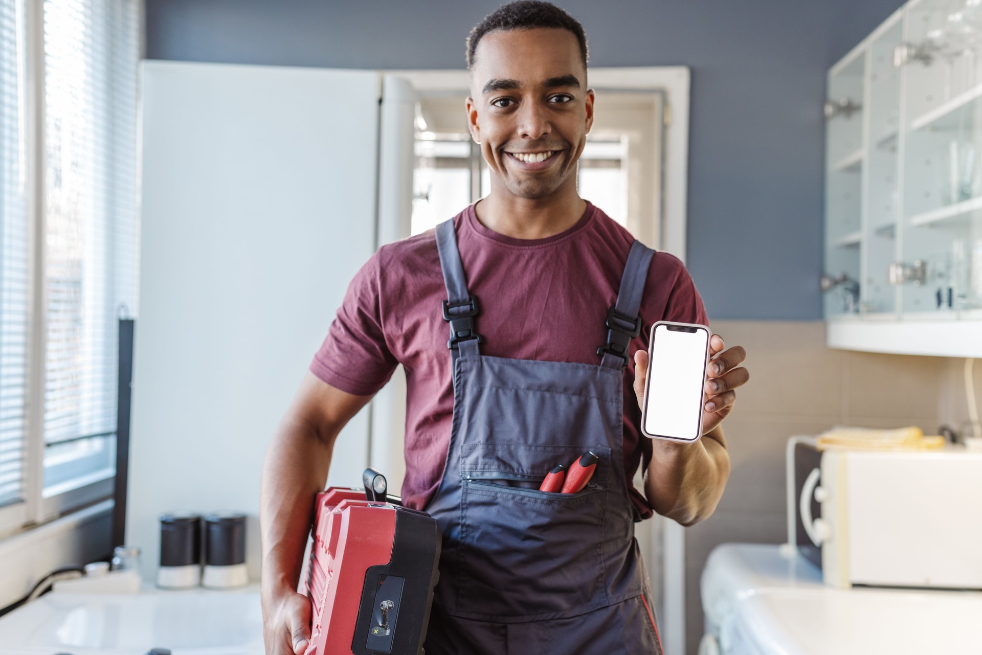 Portrait of African American handyman holding smart phone with white screen